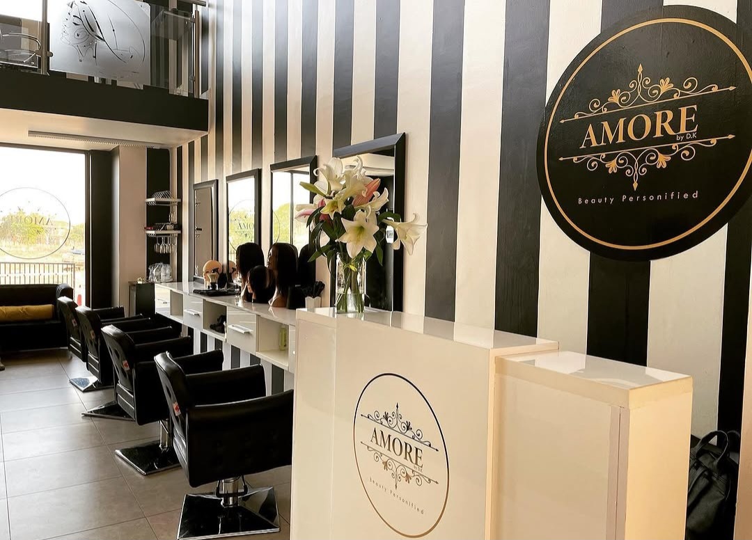 Black-and-gold salon reception with striped feature wall, styling stations and elegant gold signage